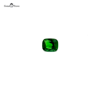 A deep green tsavorite garnet gemstone in a rectangular cut, displayed on a white turntable.