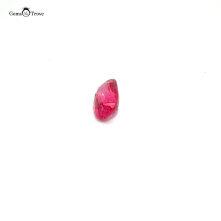 A soft pink oval-cut spinel gemstone, displayed on a white turntable.