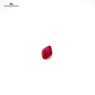 A deep red, rectangular-cut ruby gemstone displayed on a white turntable.