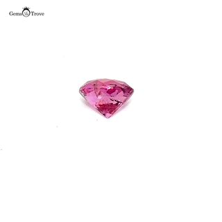 A loose pink sapphire gemstone resting on a white turntable, reflecting light beautifully.
