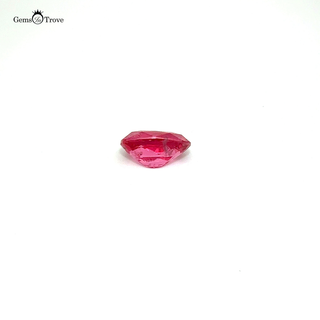 A loose pink spinel gemstone resting on a white turntable, reflecting natural light.