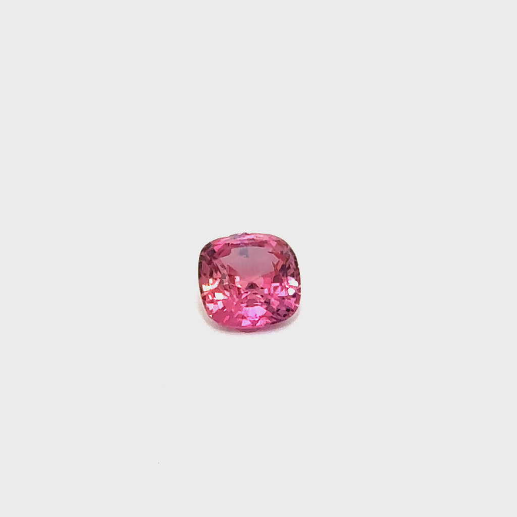 A rotating padparadscha sapphire gemstone, displaying its vibrant hues under professional lighting.