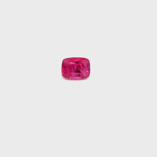 A rotating 1.15ct pinkish ruby gemstone on a white turntable, showcasing its brilliance.