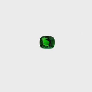 A rotating tsavorite garnet gemstone on a white turntable, highlighting its deep green brilliance.