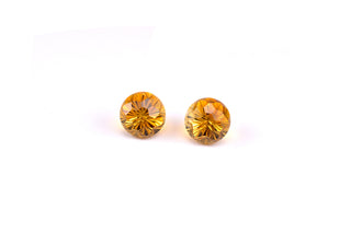 Golden citrine gemstones upright and sideways, brilliant cuts, luxurious white backdrop.