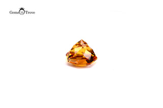Amber citrine gem with diamond-like geometric design, white background.