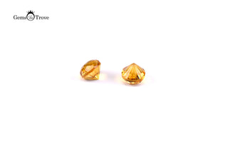 Round yellow citrine gemstones reflecting light with geometric elegance on white.