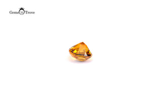 Round orange citrine gemstone, brilliant cut reflecting amber-gold hues on white.