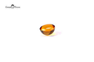 Domed citrine cabochon, golden-brown color, reflective highlights on white.